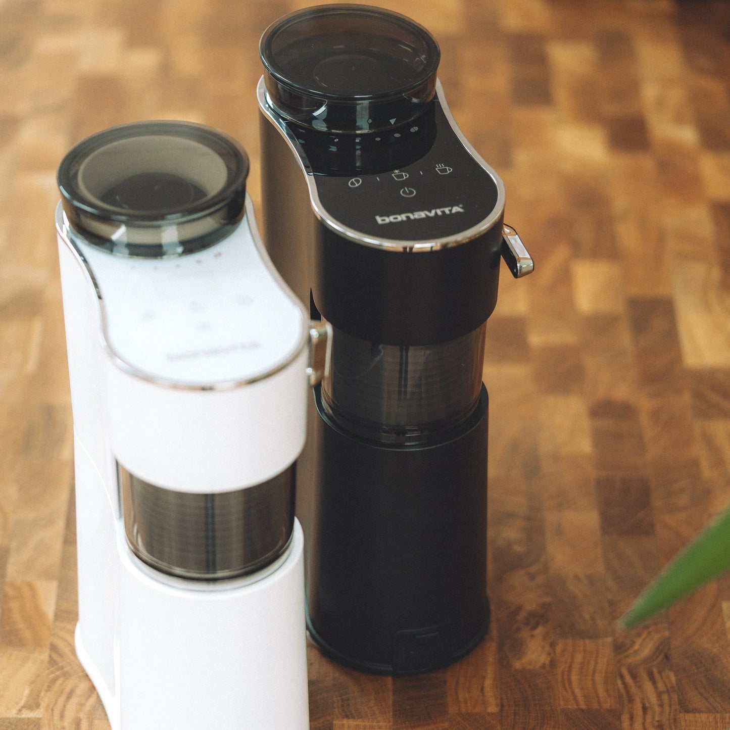 Two coffee brewing devices, one white and one black, on a wooden surface.