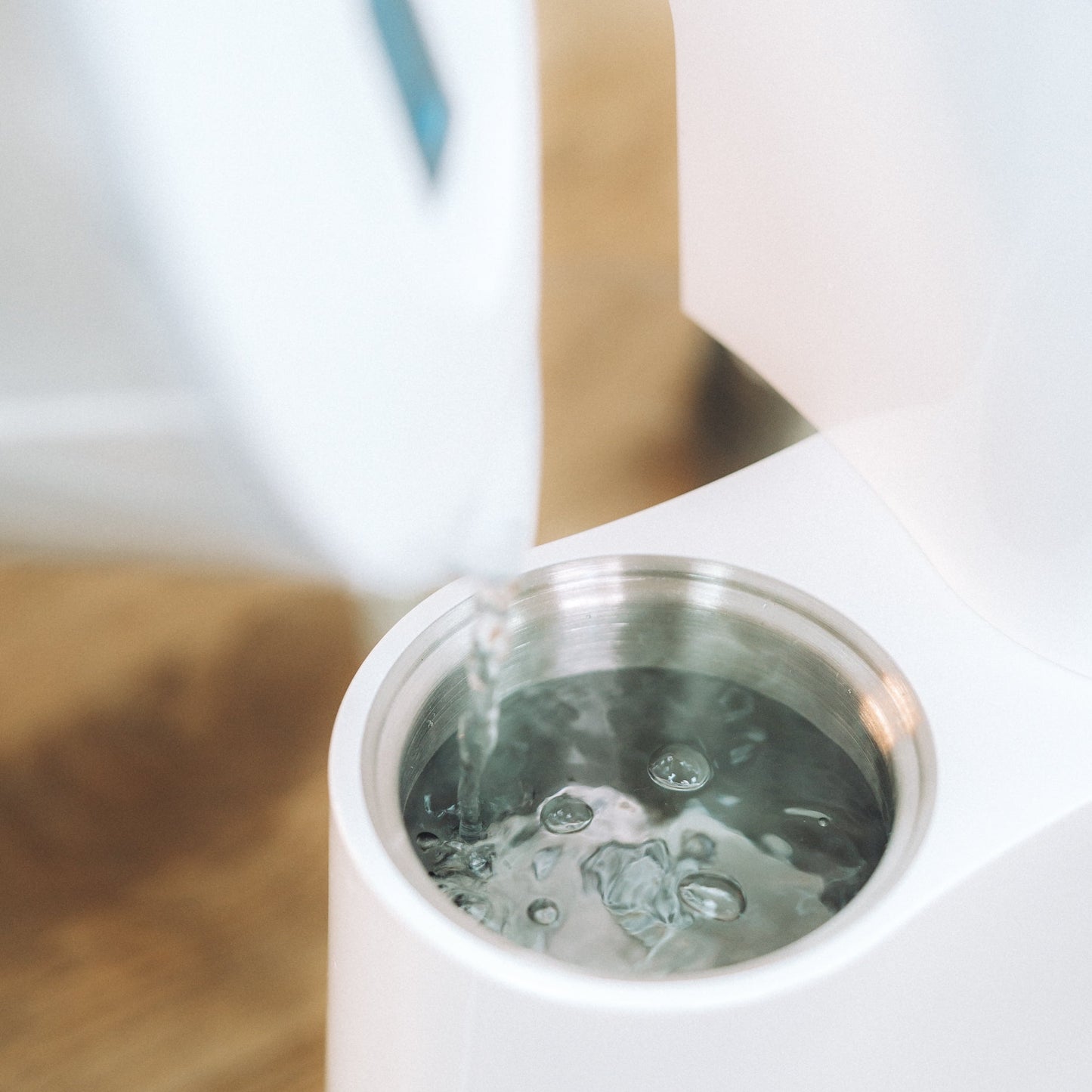 White electric kettle being filled with water on a wooden surface