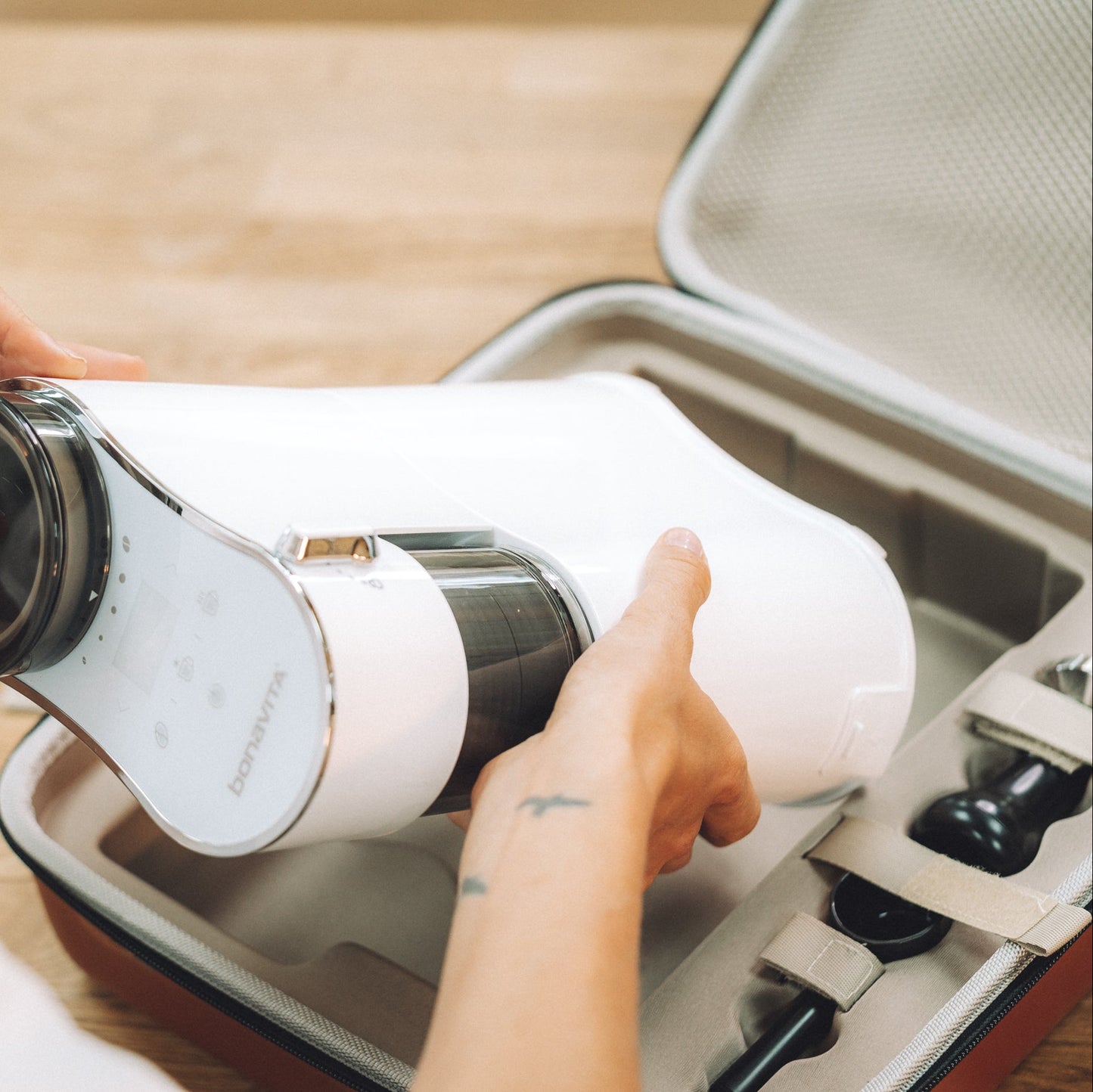 Person holding a white thermos with black lid over an open suitcase.